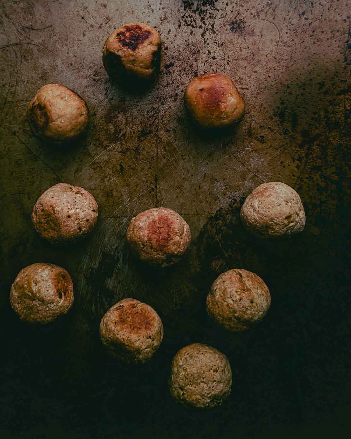 top down view of browned orbs (vegan chicken meatballs) on a distressed metal background