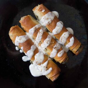 3 golden vegan borek with spinach filling and yoghurt drizzled over top