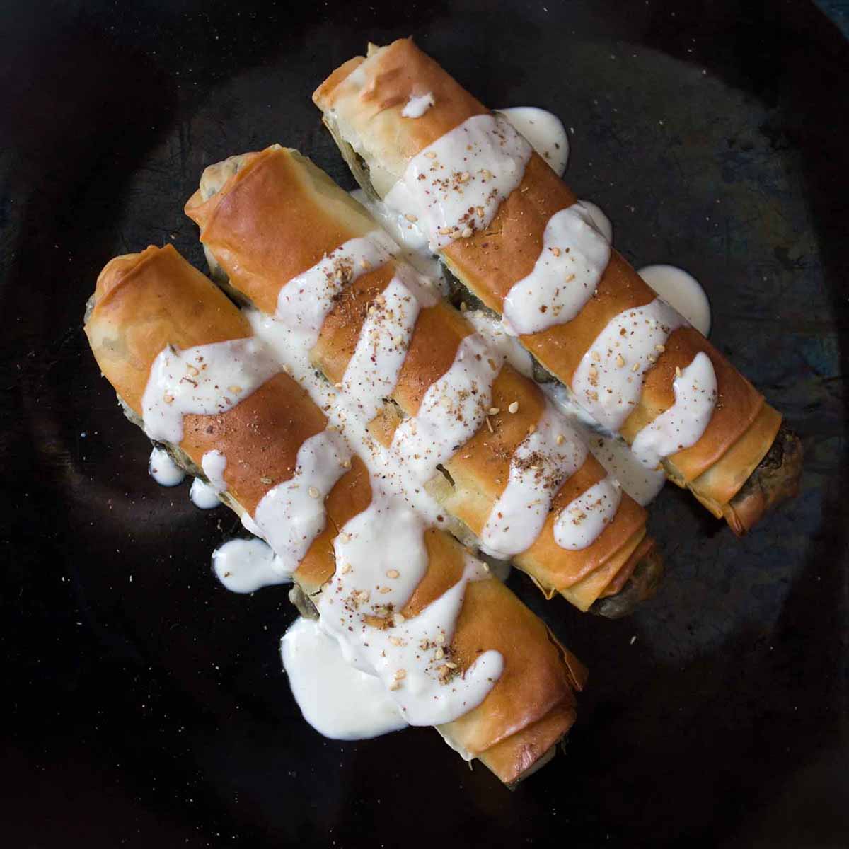 3 golden vegan borek with spinach filling and yoghurt drizzled over top