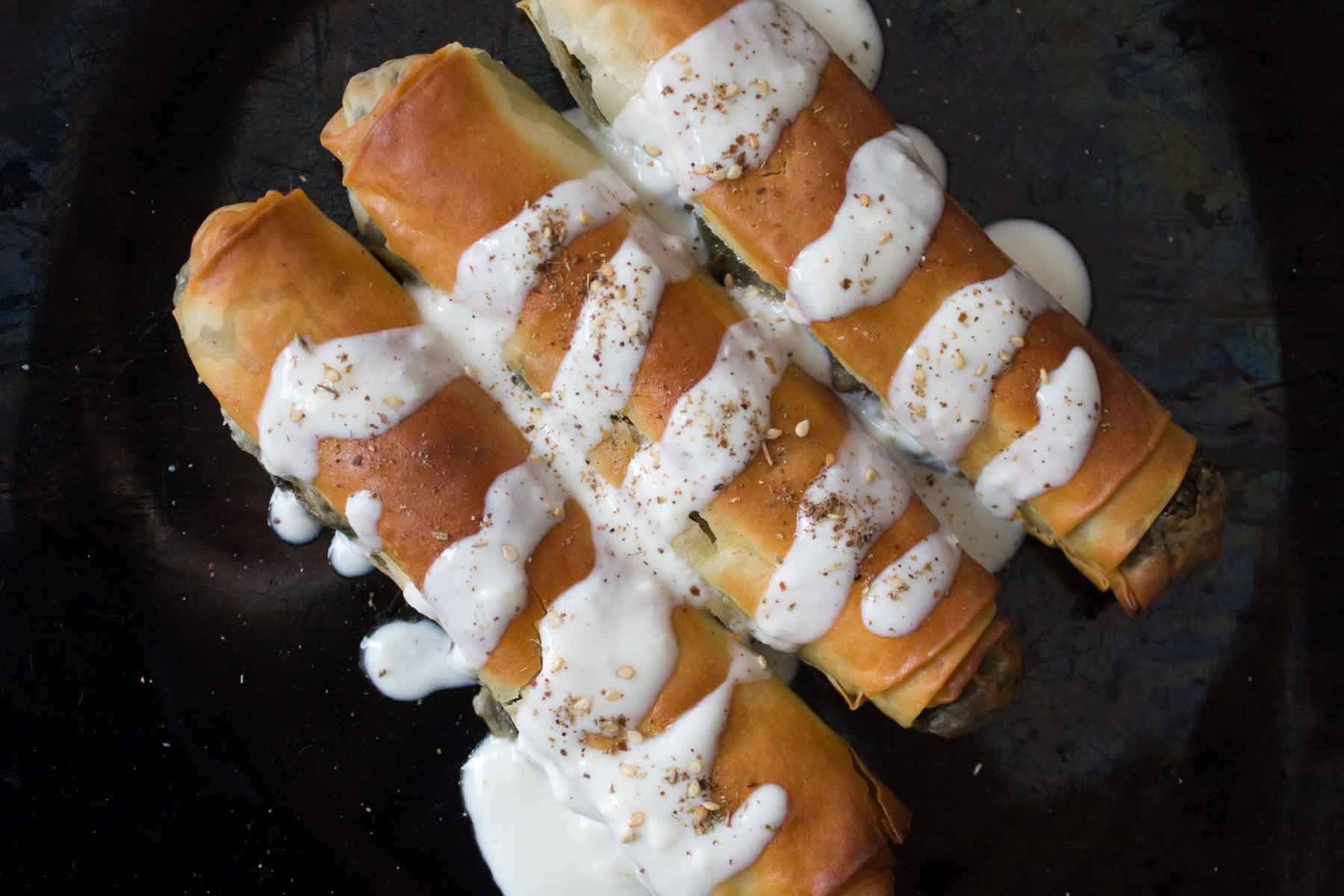 3 golden vegan borek with spinach filling and yoghurt drizzled over top