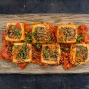 Top down view of 6 pieces of lemongrass stuffed tofu on a brown rectangular plate