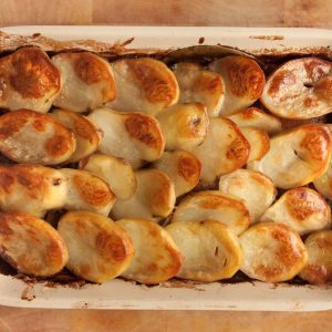 top down view of a rectangular tray of vegan lancashire hotpot topped with crispy golden potato slices