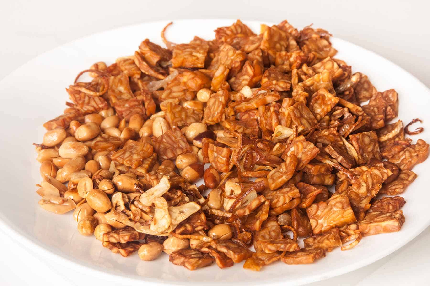 Plate full of beige fried items, including tempeh and peanuts