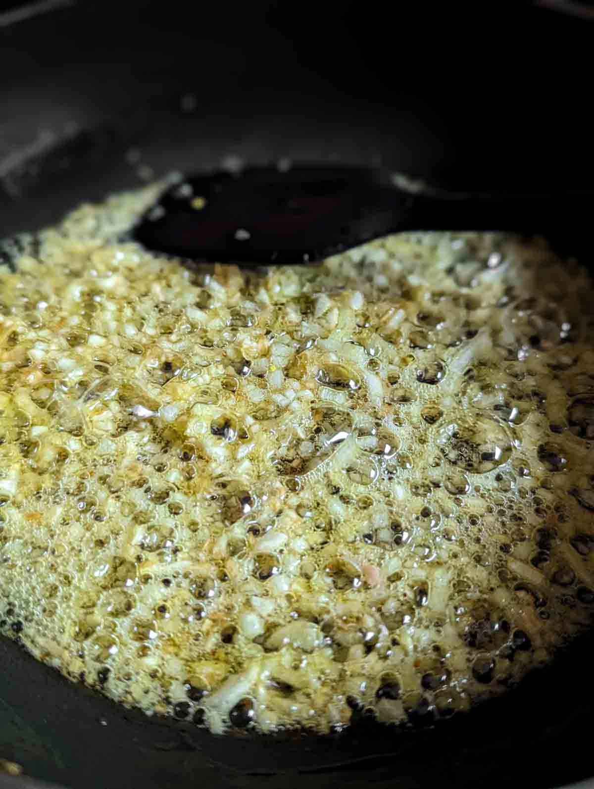 Close up of pan with garlic and onion frying