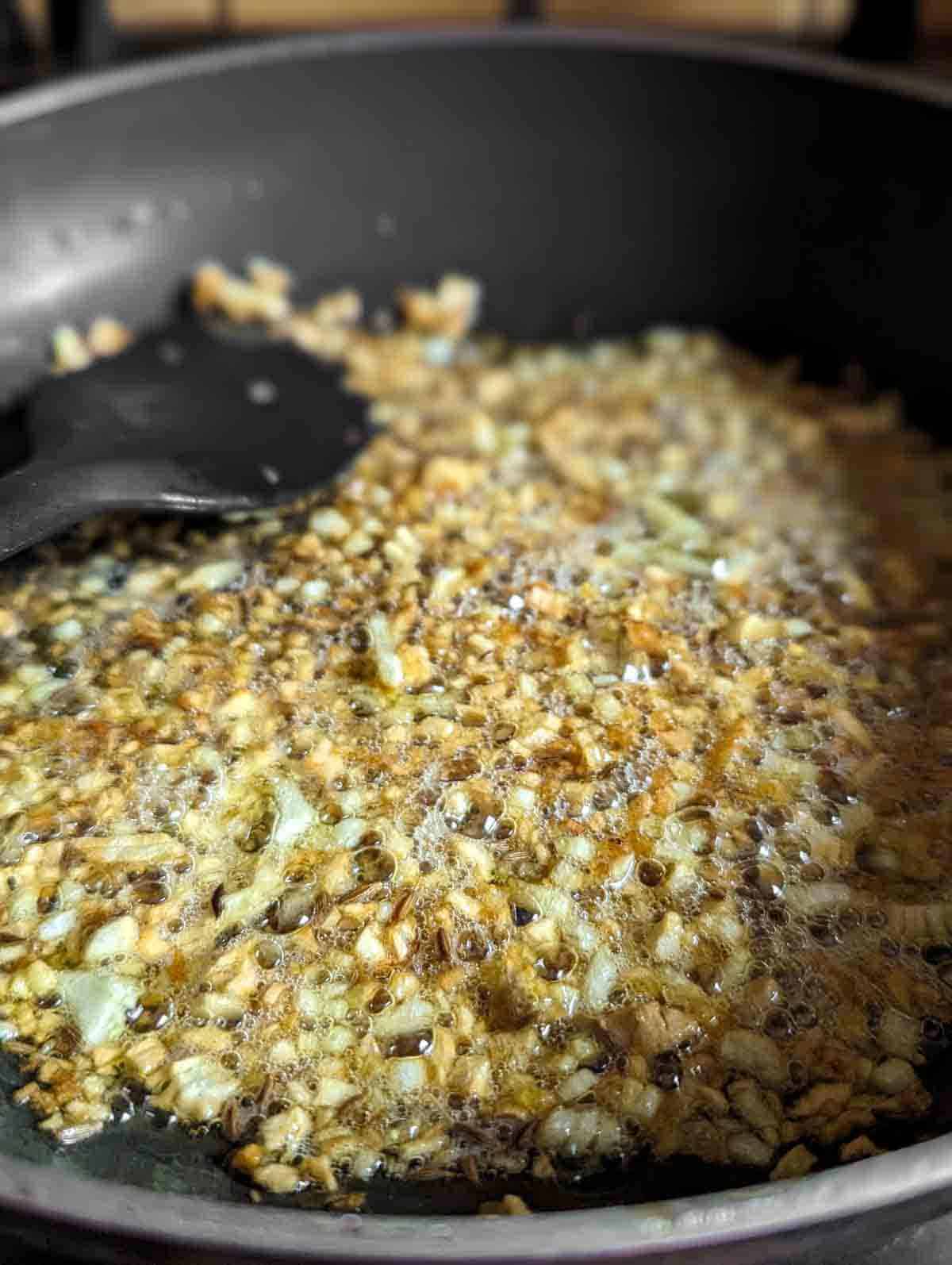 Close up of pan with garlic and onion frying