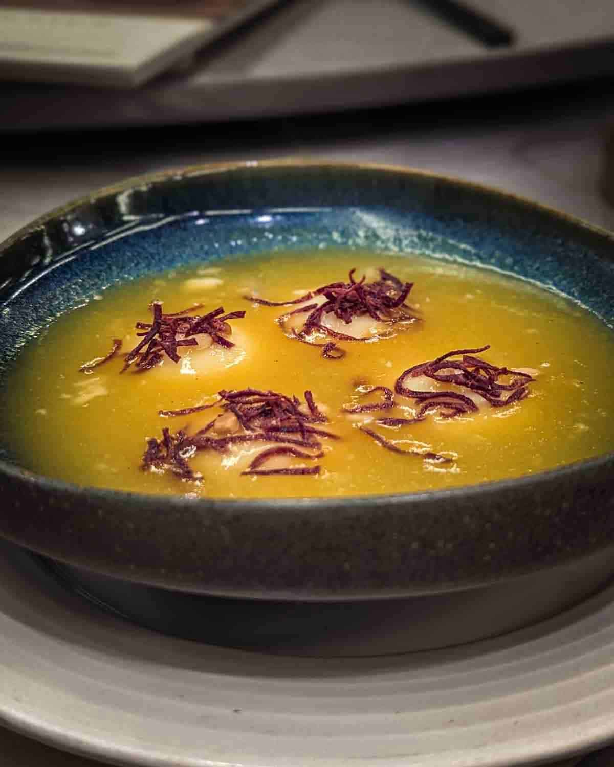 View from the side of a bowl of pumpkin and sweet potato soup in a restaurant