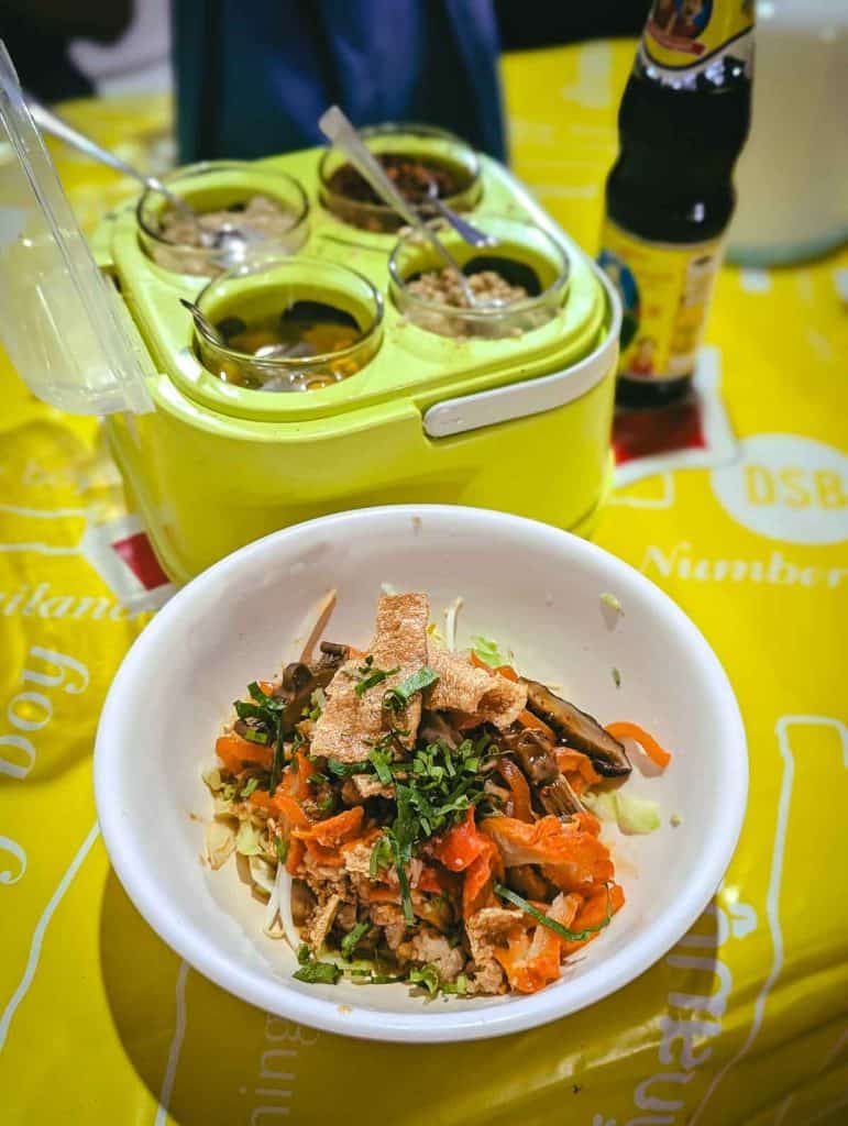 bowl of noodles (dry, withour soup), alongside a condiment caddy