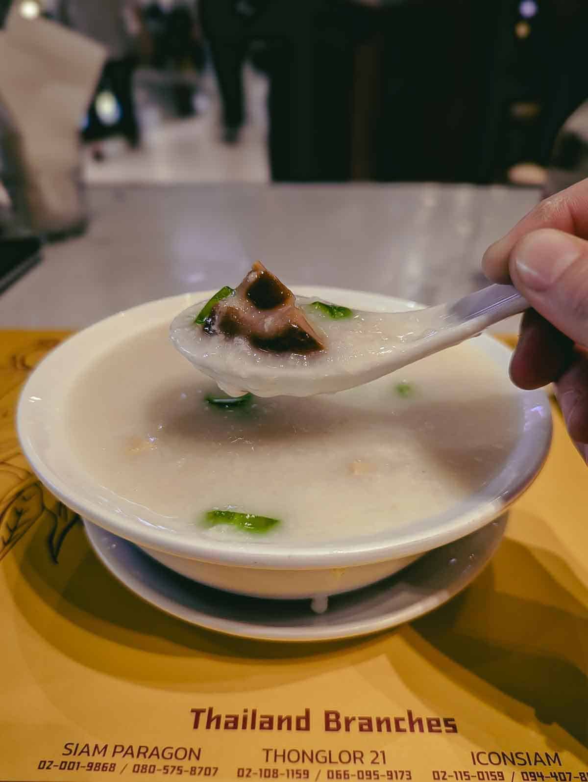 bowl of thin white rice porridge with a Chinese soup spoon