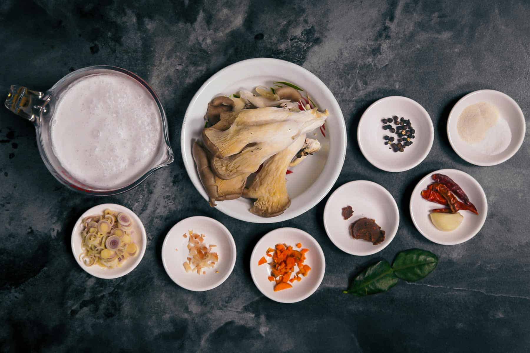 Ingredients laid out in bowls and small white ramekins for making vegan kanom jeen nam ya.