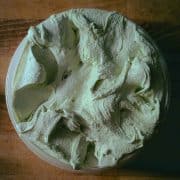 Top down view of a round plastic container filled with light green ice cream