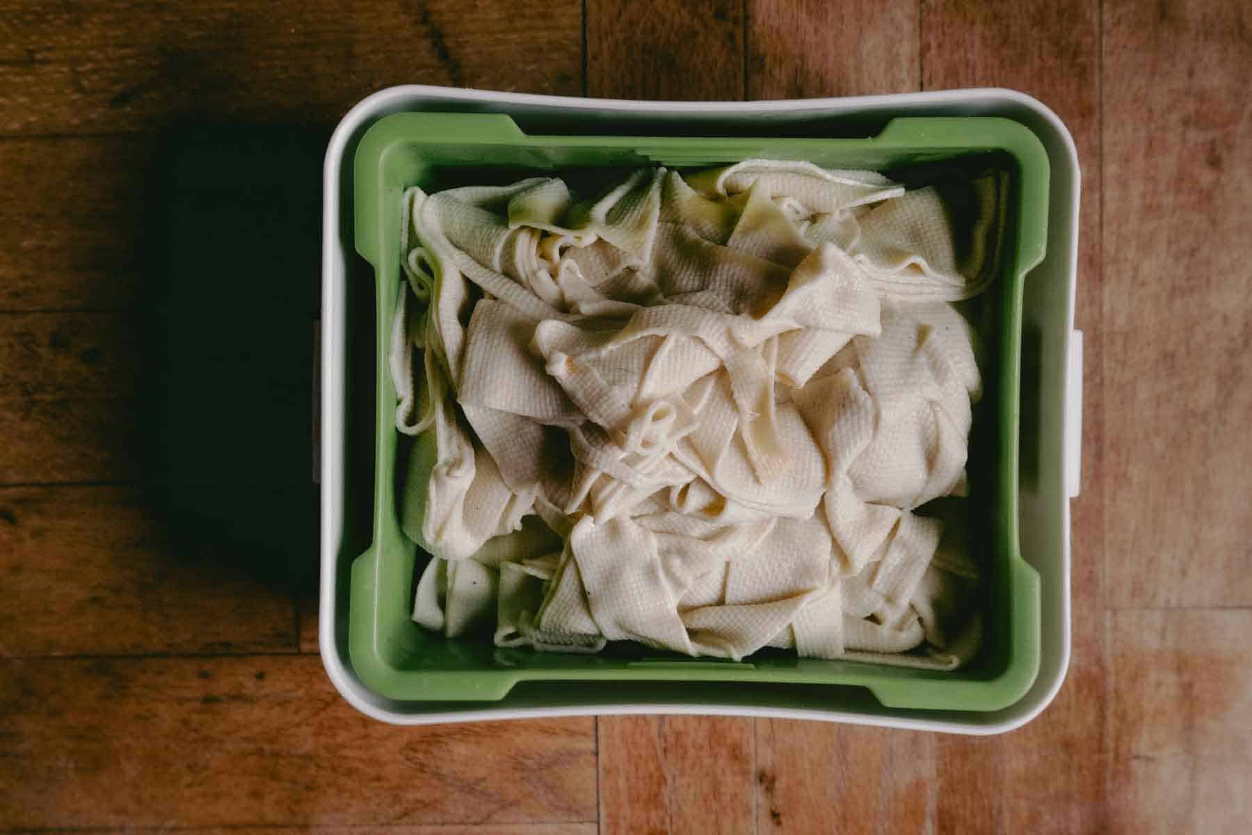 thin beige strips piled into a green tofu press