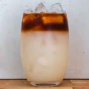 glass ⅘ full with white-ish liquid. The top ⅕ is coffee