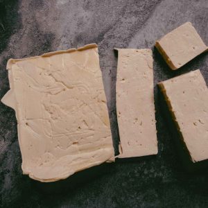 top down view of a rectangle of vegan chicken tofu, along with a few slices cut off, on a dark grey surface