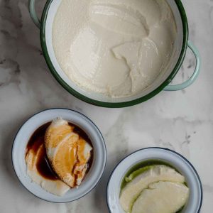 Top down view of a large pot with tofu pudding, next to two small bowls with tofu pudding.